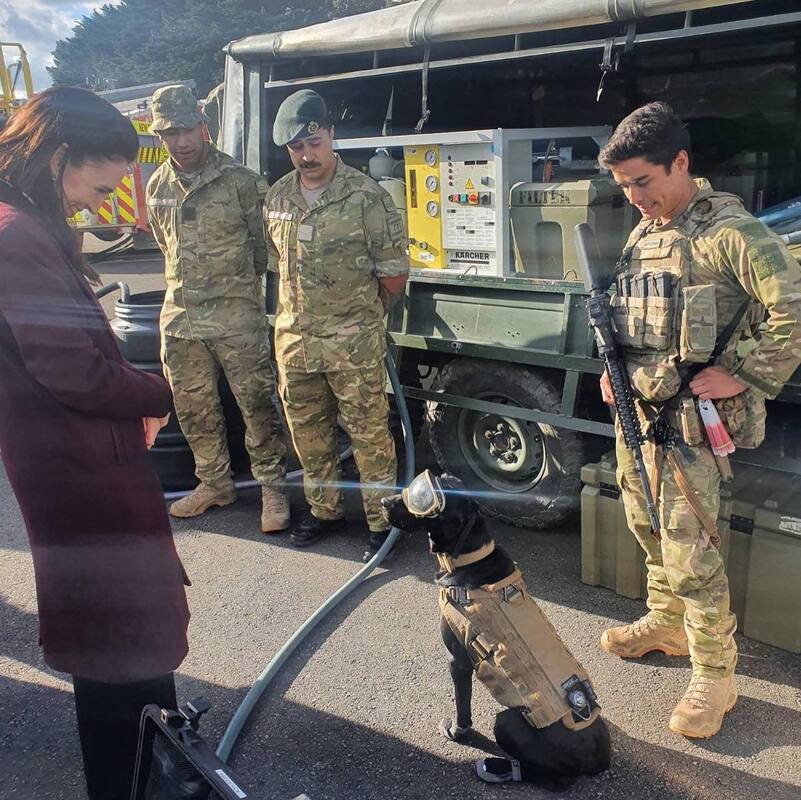 Photo of Pet Transport NZ clients from New Zealand Defence Force. A working dog plus 3 men from NZDF with the Prime Minister.